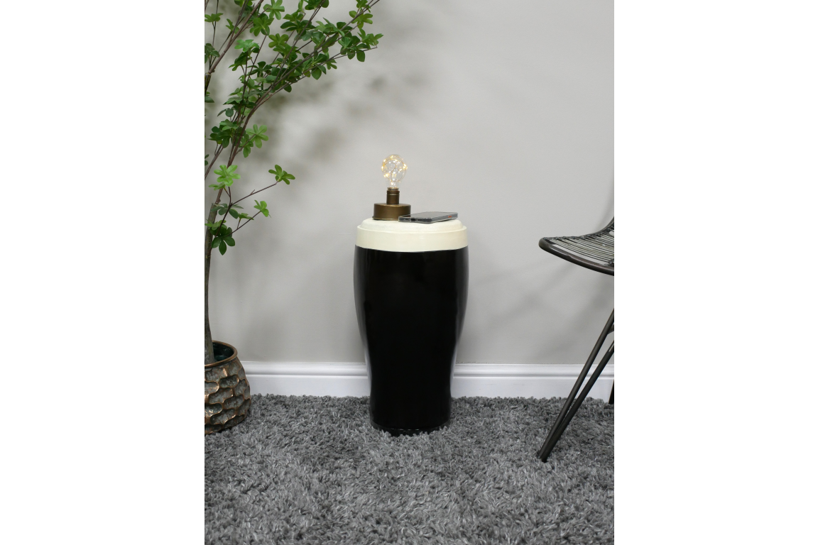 Black and white ceramic stout side table with lamp and smartphone on top, shown in a carpeted room corner from front angle.