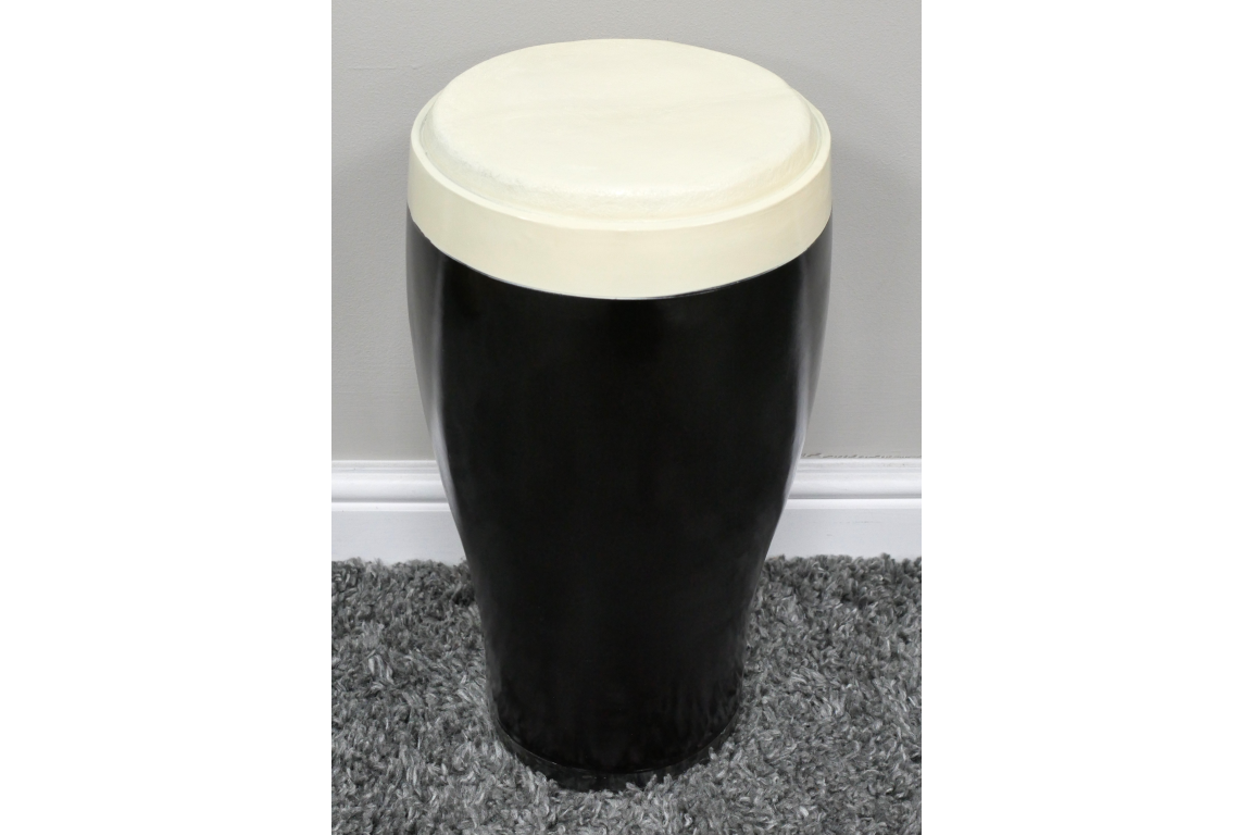 Black and white ceramic stout side table with rounded top, cylindrical shape, shown on gray carpet against beige wall.