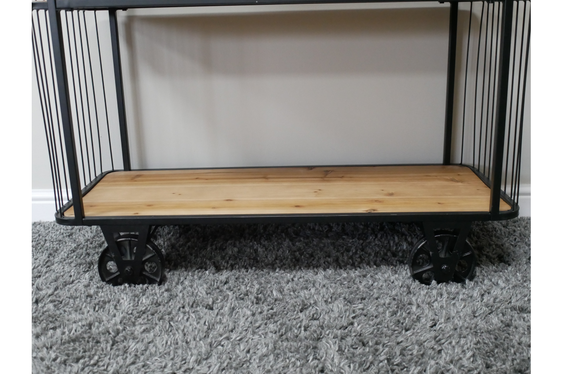 Black metal frame shelves with light wood base and industrial style black wheels on grey carpet floor.