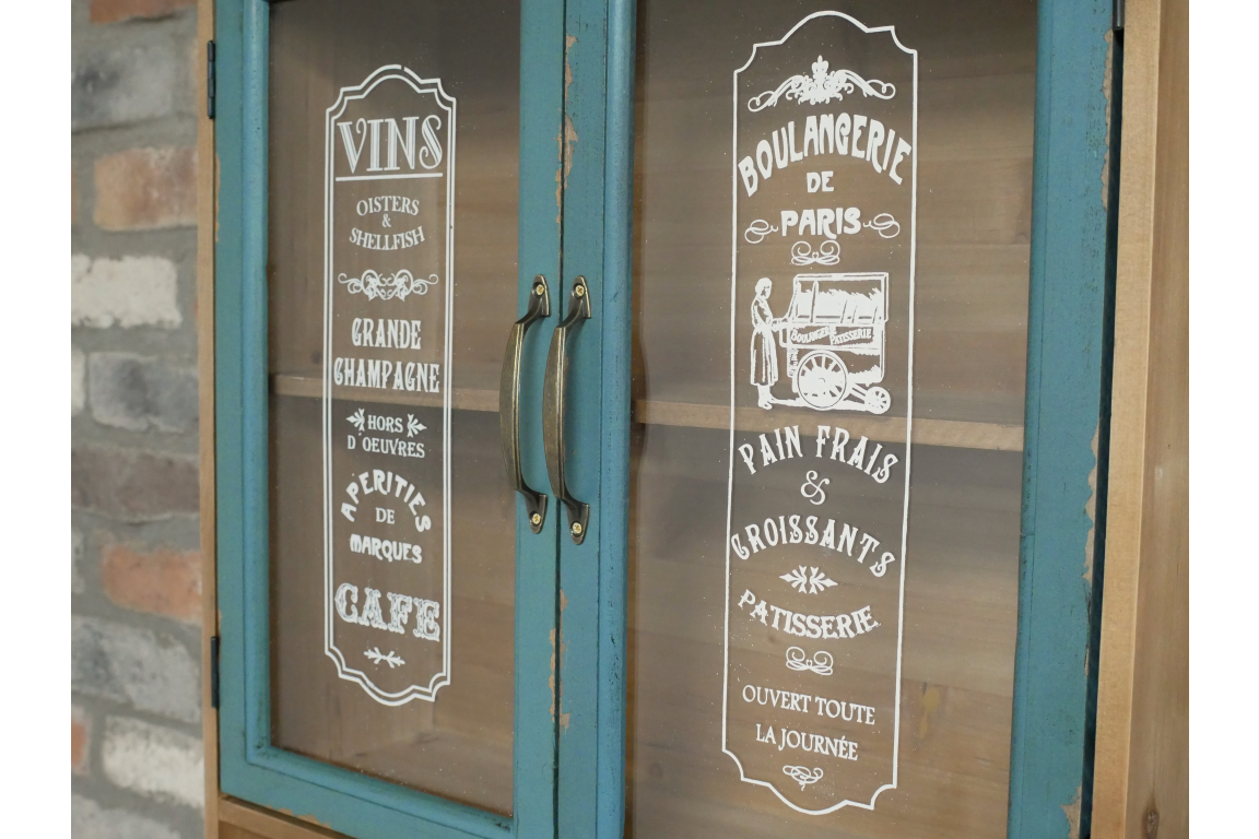 Wooden wall unit with blue distressed framed glass doors showing white vintage French bakery signs.