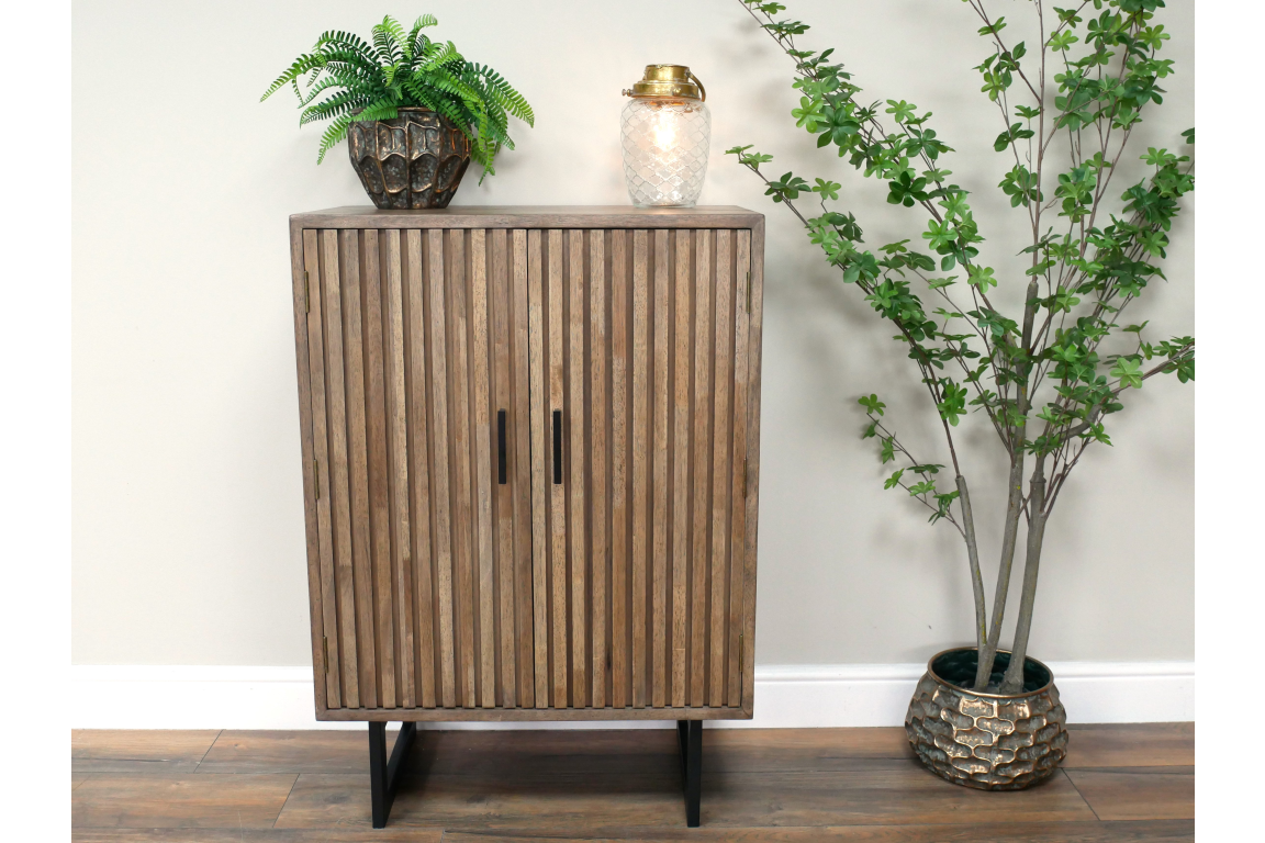 2 Door slatted wooden cabinet in light brown with black handles and legs, shown front view in a room setting.
