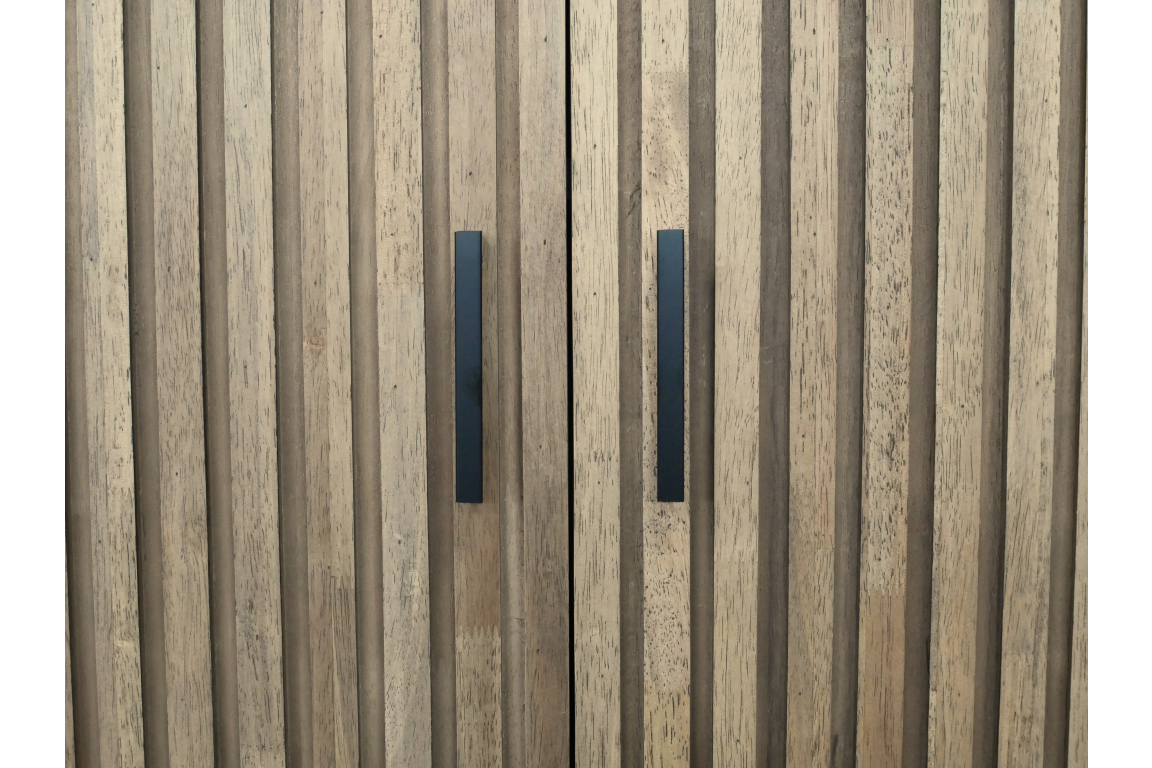 Close-up view of light brown wooden 2 door slatted cabinet with black vertical handles.