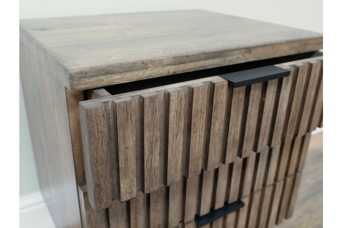 Slatted bedside cabinet in natural wood finish with two drawers, angled view showing texture and black handles.