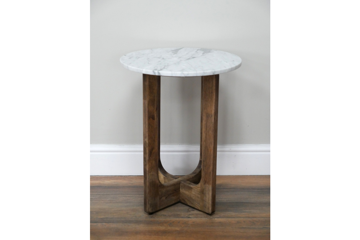 Small round side table with white marble top and wooden interlocking legs, shown front on against a wall.