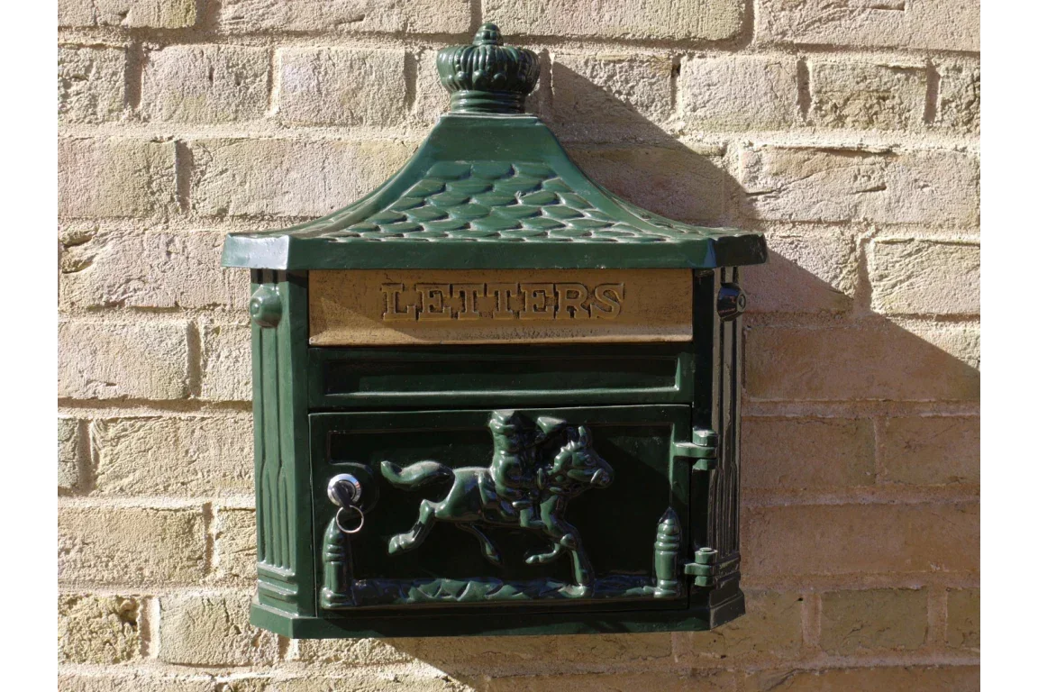 Green cast iron wall mounted letterbox with gold mail slot and horse rider motif