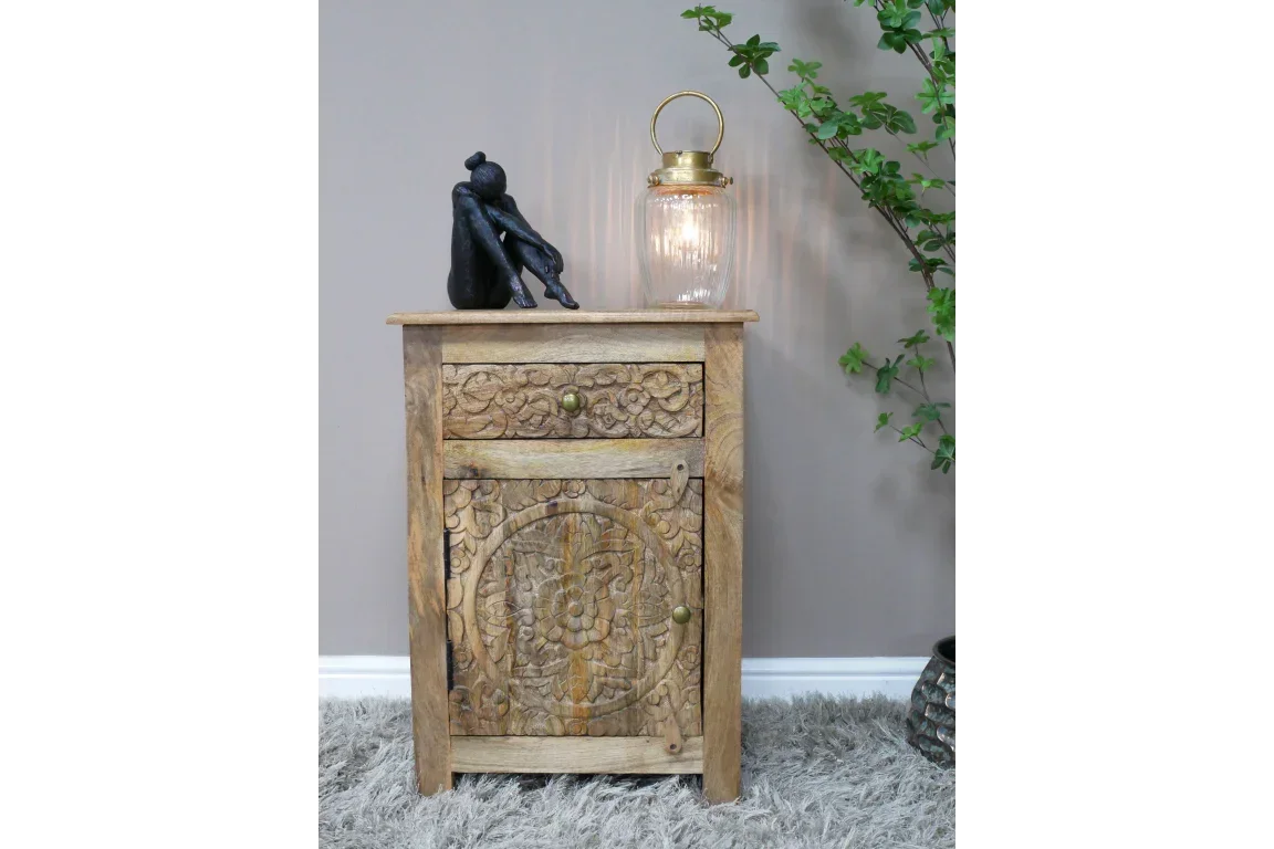 Carved wood bedside cabinet with brass handles, lantern, and black sculpture on top