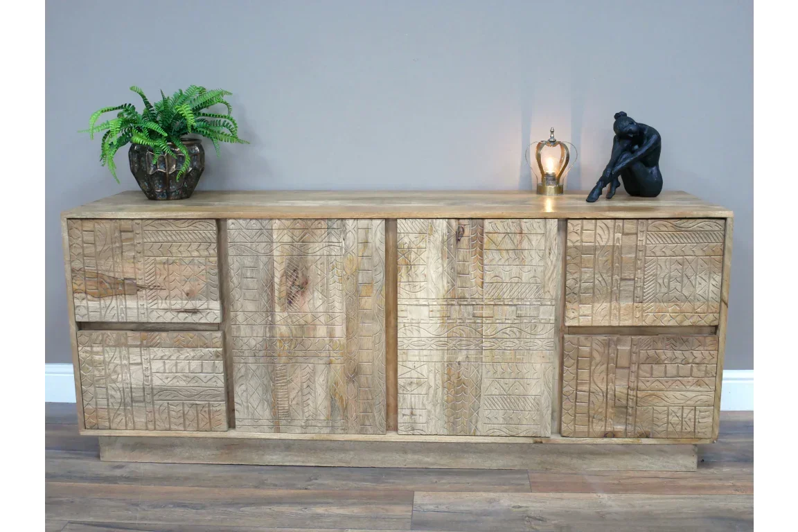 Carved wood sideboard with patterned doors, potted plant and decor on top
