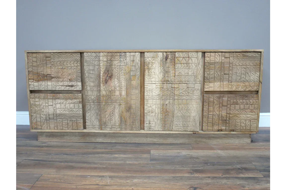 Carved wooden sideboard with geometric patterns and natural wood finish on wood flooring