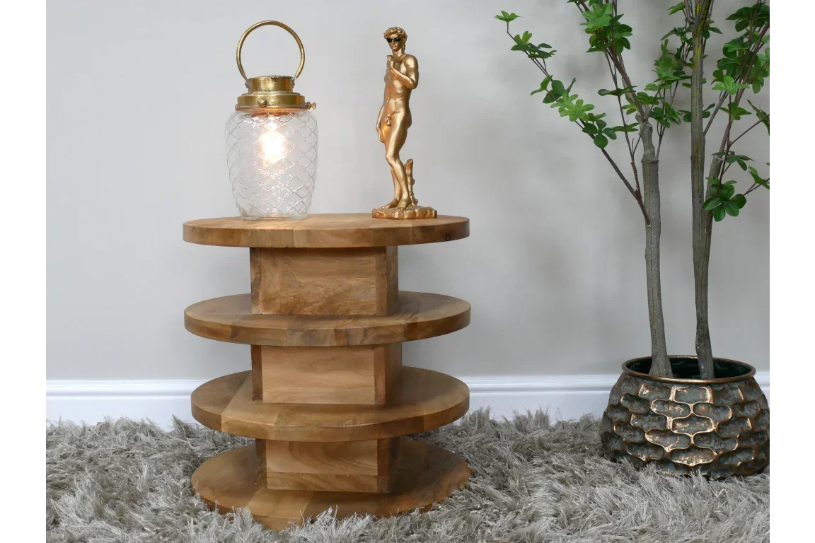 Round wooden side table with tiered shelves on grey rug beside potted plant