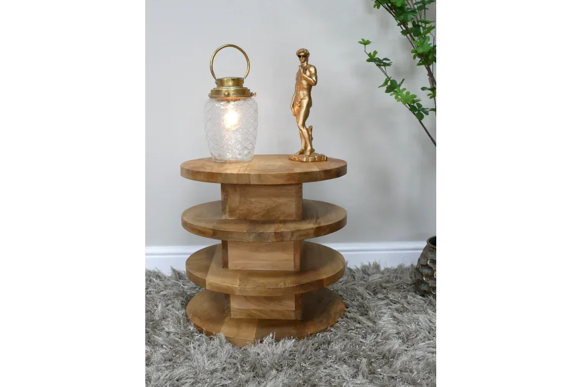 Round tiered wooden side table on grey shag rug with lamp and gold sculpture
