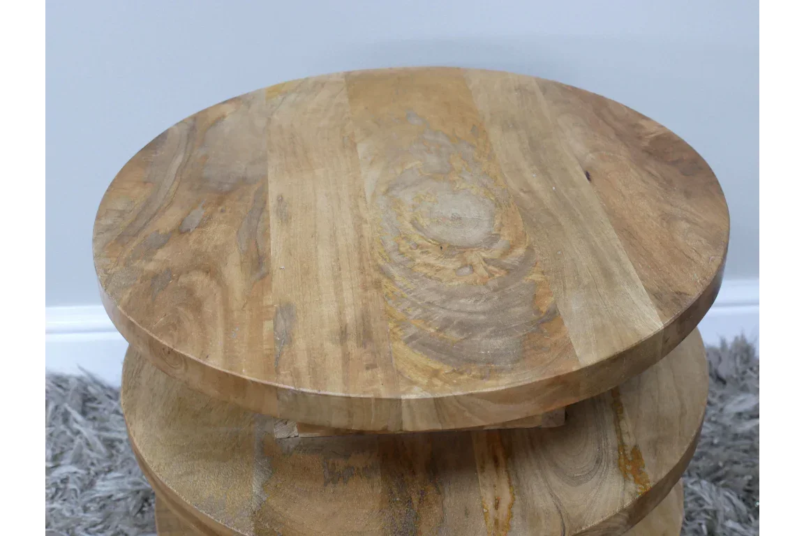 Round wooden side table with natural wood grain, placed on a grey textured rug