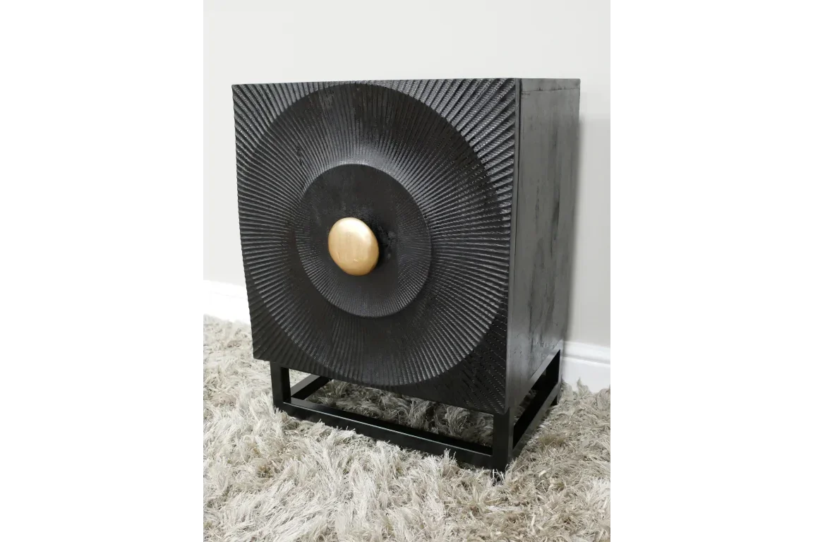 Black wooden side table with textured circular front and gold handle on shag rug