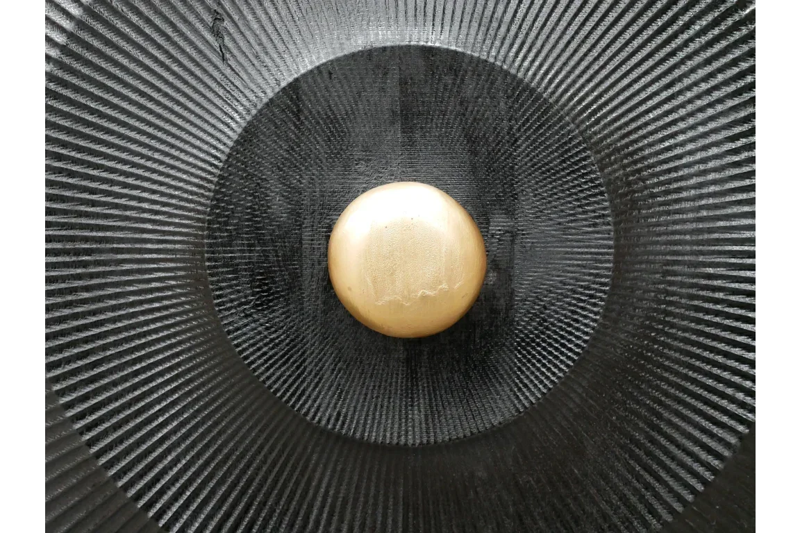 Decorative black metal wall art with gold central disc and textured, radial pattern