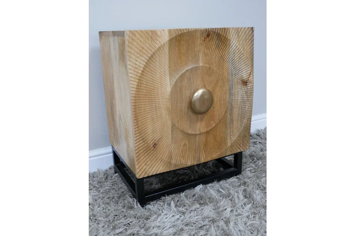 Wooden bedside cabinet with carved circle detail and metal base on grey carpet