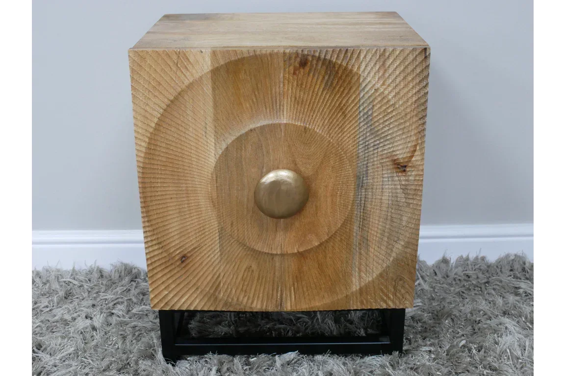 Contemporary wooden side table with geometric carved front and metal base on grey rug