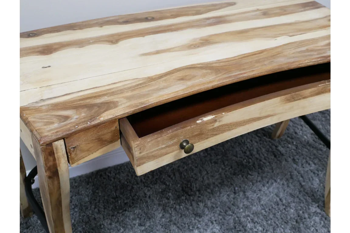 Solid wood desk with single open drawer, curved front edge, and natural finish on carpet