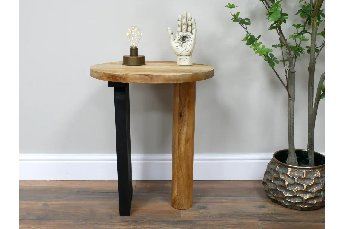 Wooden side table with round top, black metal leg and decor, placed on wooden floor