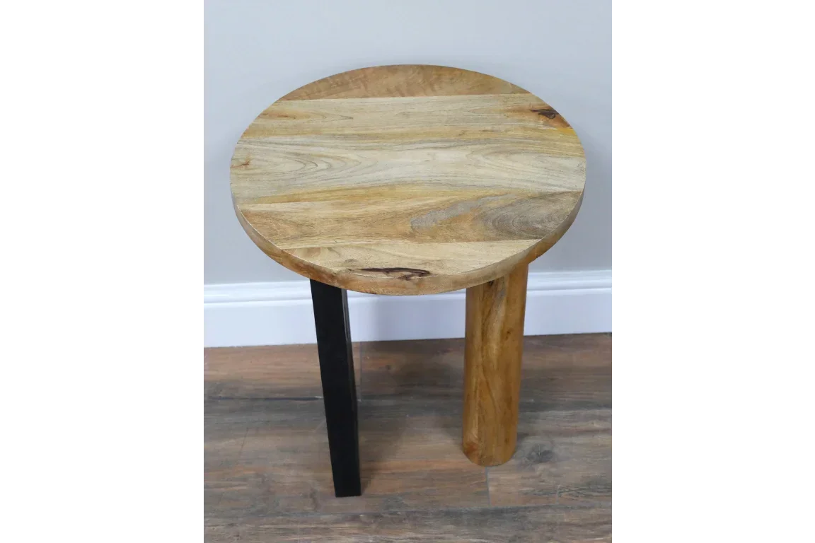 Round wood side table with mixed metal and wood legs, placed on wooden floor