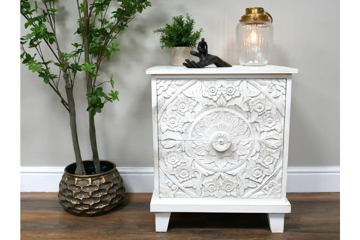 White carved wooden bedside table with floral mandala design, styled beside plant and lamp