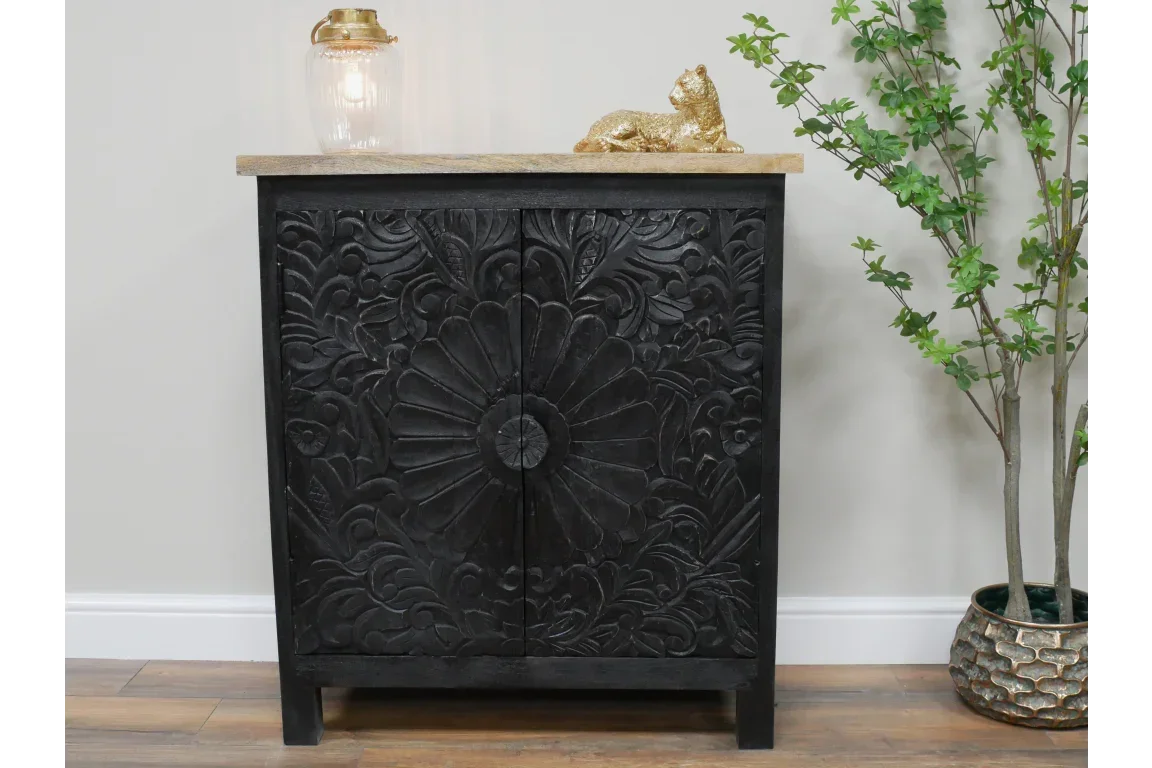 Black carved wood cabinet with floral pattern, natural top, styled with gold cat and lamp