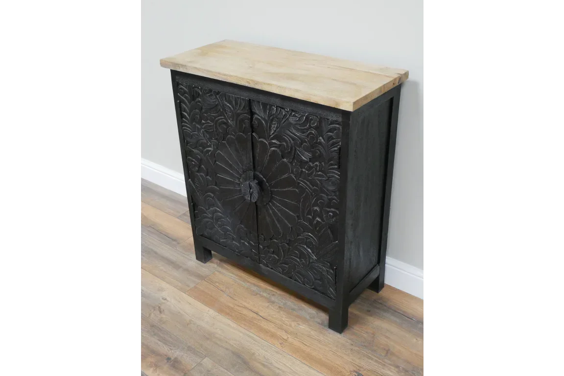 Black carved wooden cabinet with floral pattern and light wood top on laminate floor
