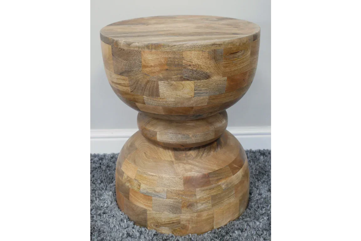 Round solid wood side table with natural finish on grey carpet