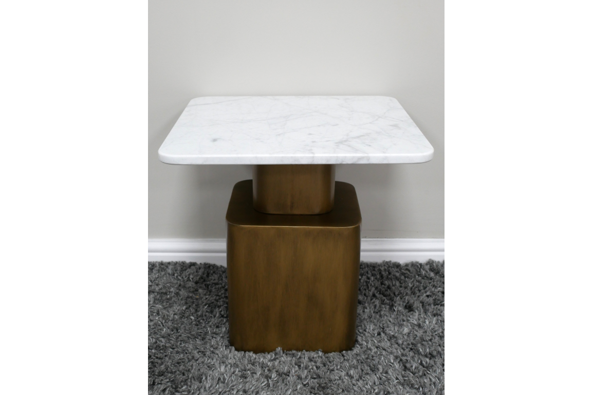 Square side table with white marble top and bronze metal base on gray shag carpet, front view.