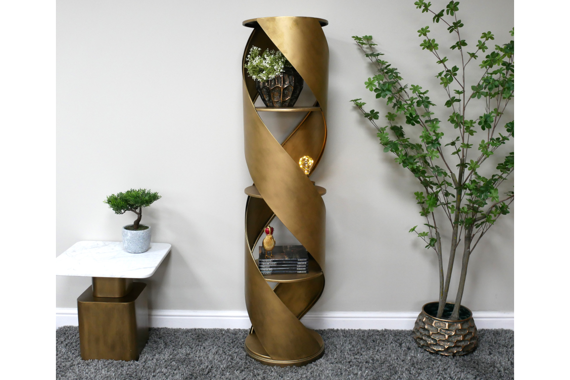 Tall bronze metal swirl display cabinet with three shelves, shown in a living room setting with plants and a side table.