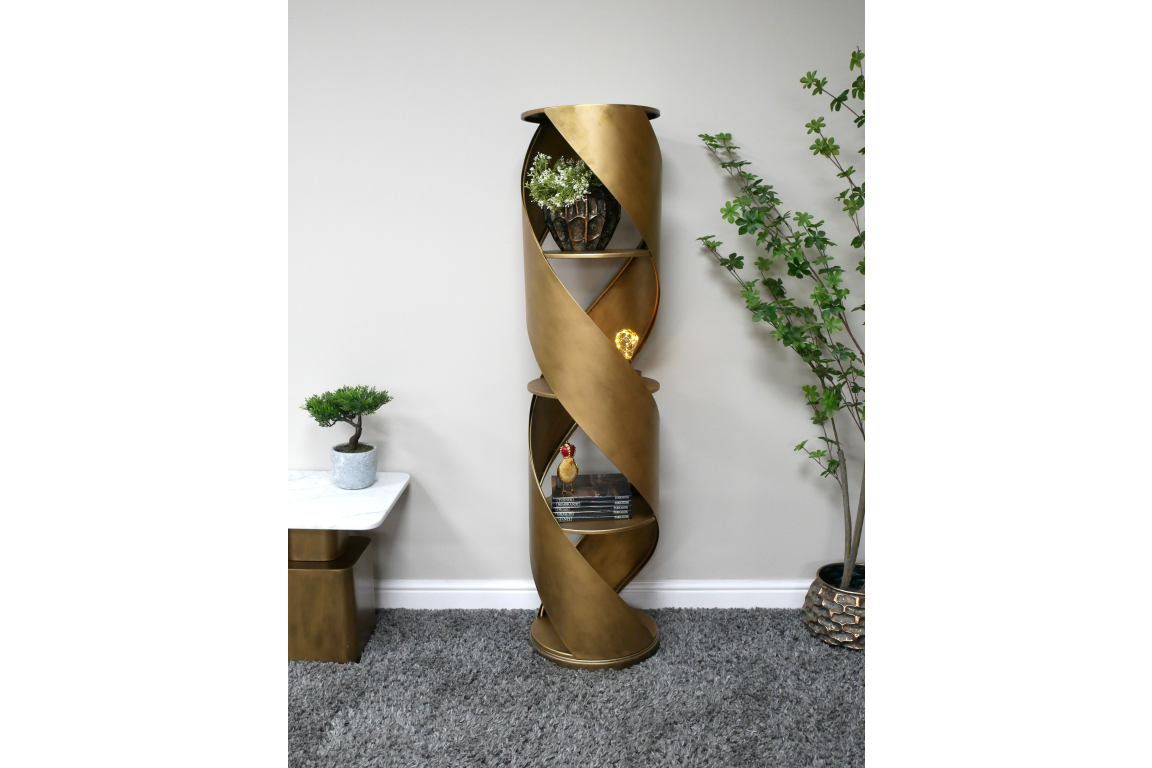 Tall gold metal swirl display cabinet with three shelves, shown in a minimalist room setting from the front angle.