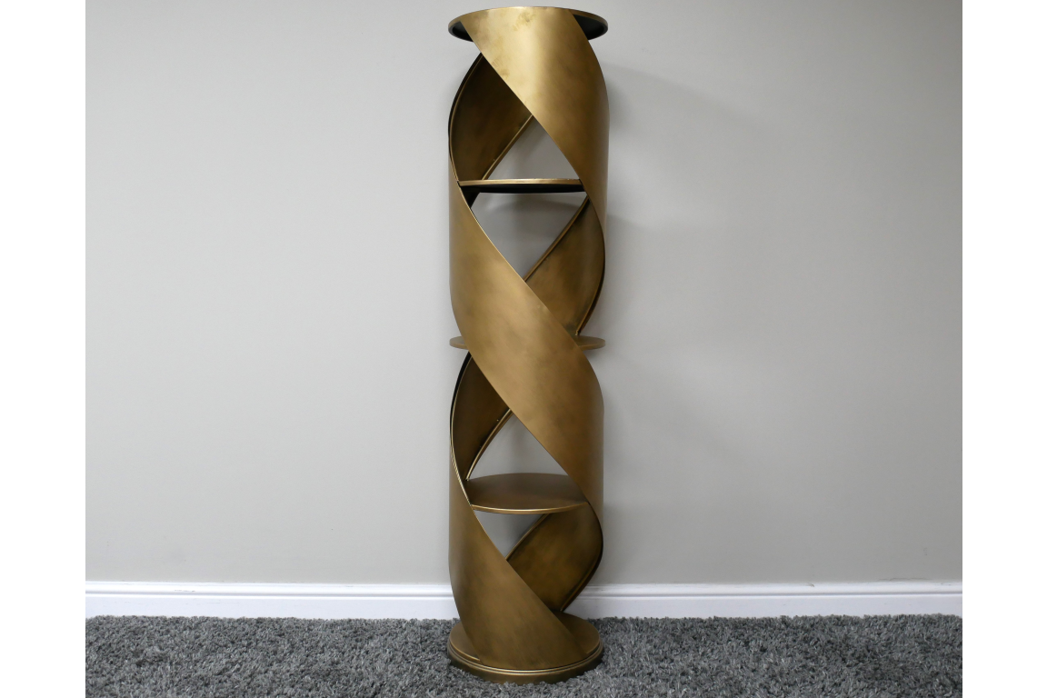 Tall swirl display cabinet in bronze metal with spiral design and three shelves, standing against a plain wall on gray