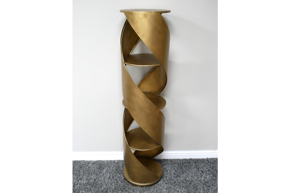 Tall spiral display cabinet in brass-colored metal with circular shelves, shown from front angle against white wall.