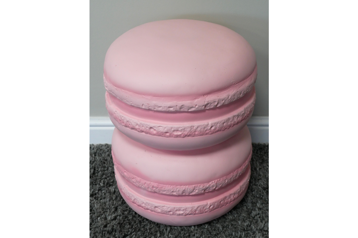 Pink macaron-shaped side table with textured edges, shown from an angled top view on gray carpet.
