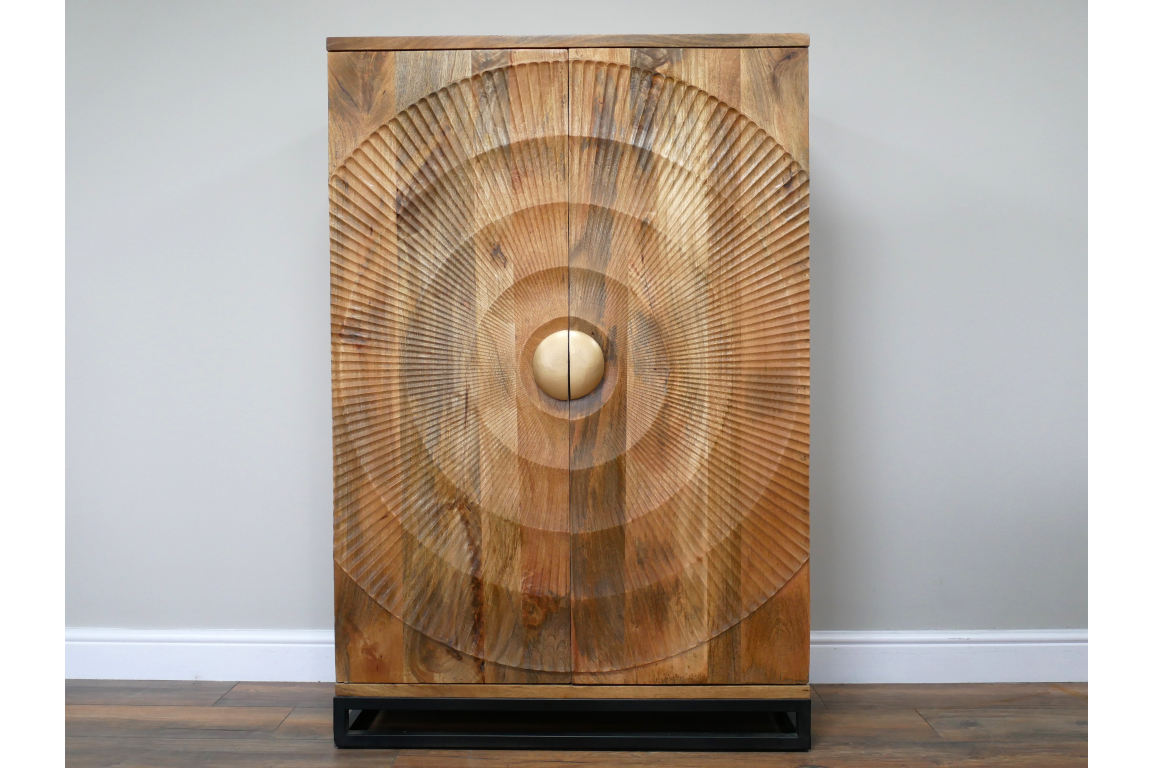 The Solstice Wine Cabinet features a natural wood finish with a striking circular carved design and a round gold knob, resting on a sleek black base