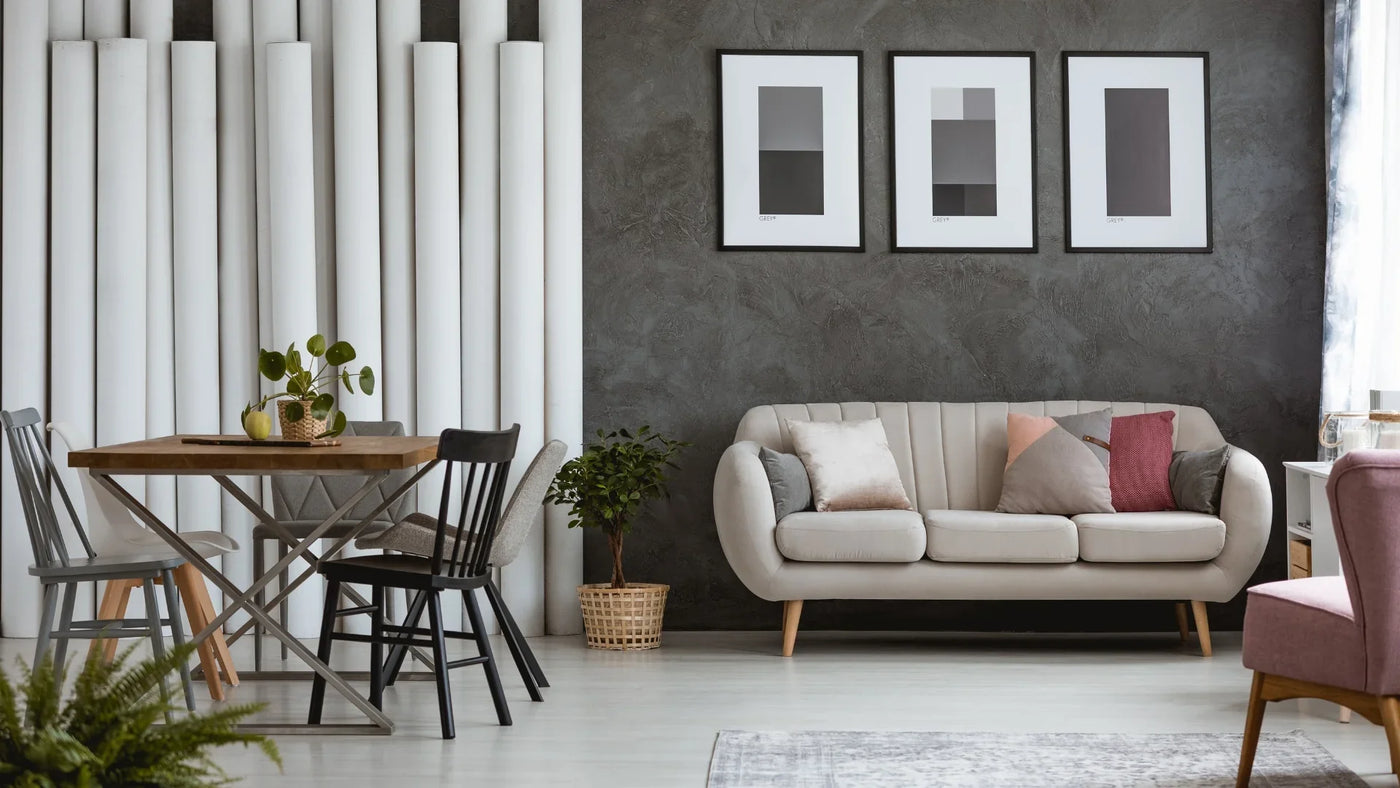 Modern beige sofa with accent cushions in living room, dining set and abstract wall art