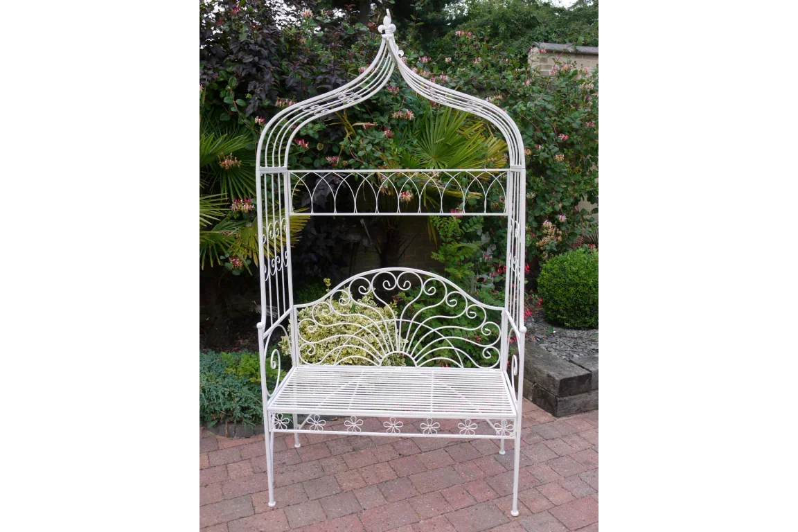 White metal garden bench with decorative arch and scrollwork on patio