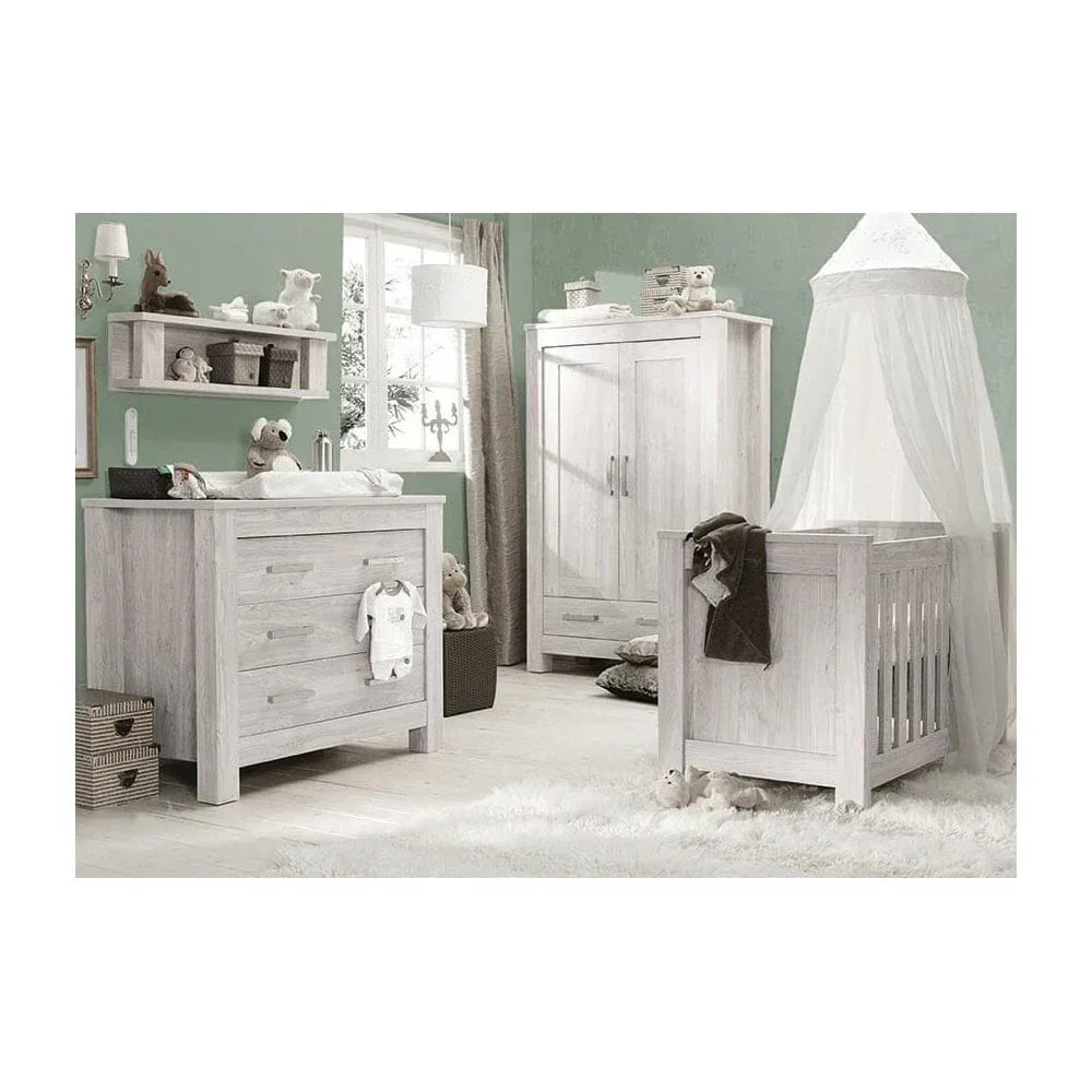 Light wood nursery furniture set with cot, wardrobe, and dresser in a soft green room