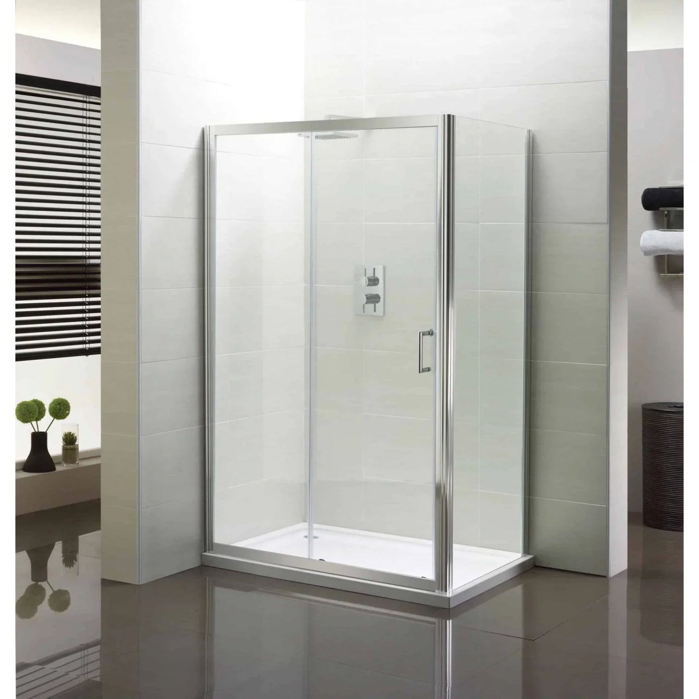 Frameless glass shower enclosure with chrome trim in a modern tiled bathroom