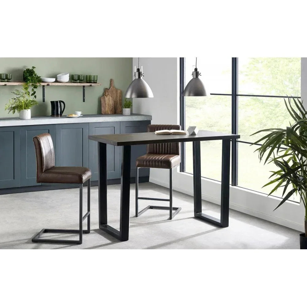 Industrial dining table with black legs and two brown leather chairs in modern kitchen