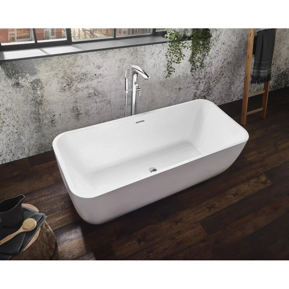 Freestanding white bathtub with chrome tap on dark wood flooring in modern bathroom