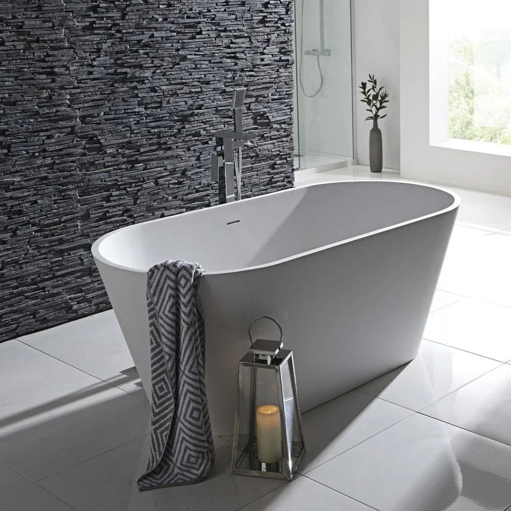 Freestanding white bathtub with towel, lantern, and slate feature wall in modern bathroom