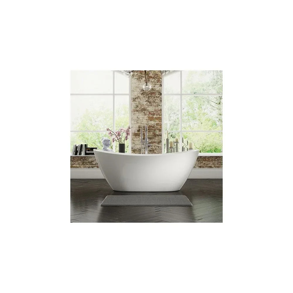 Freestanding white bathtub with chrome tap in modern bathroom with brick wall and large windows