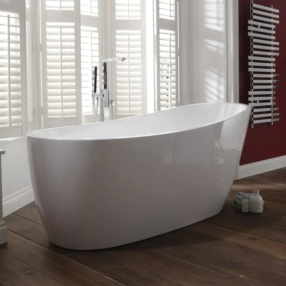Freestanding white bathtub with chrome tap in front of large windows and wood flooring