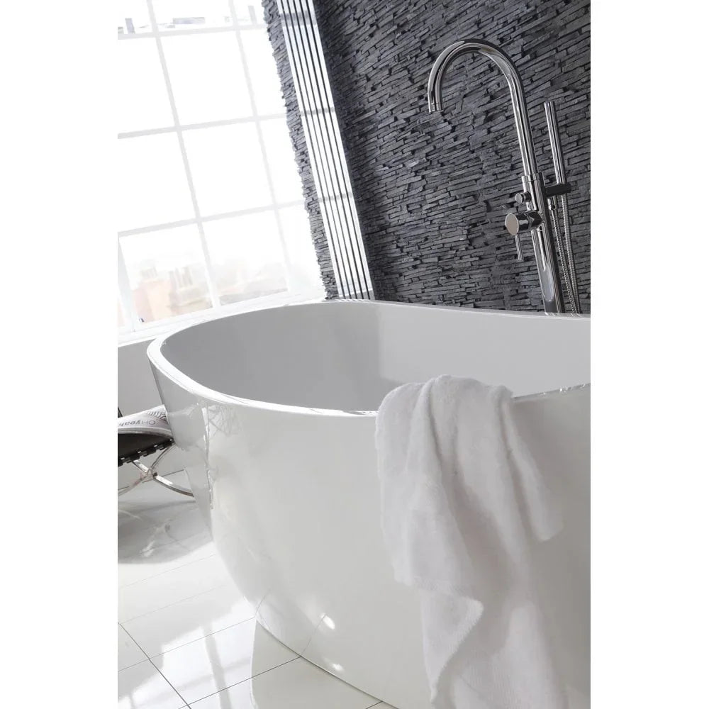 Freestanding white bathtub with chrome tap against black stone wall in modern bathroom