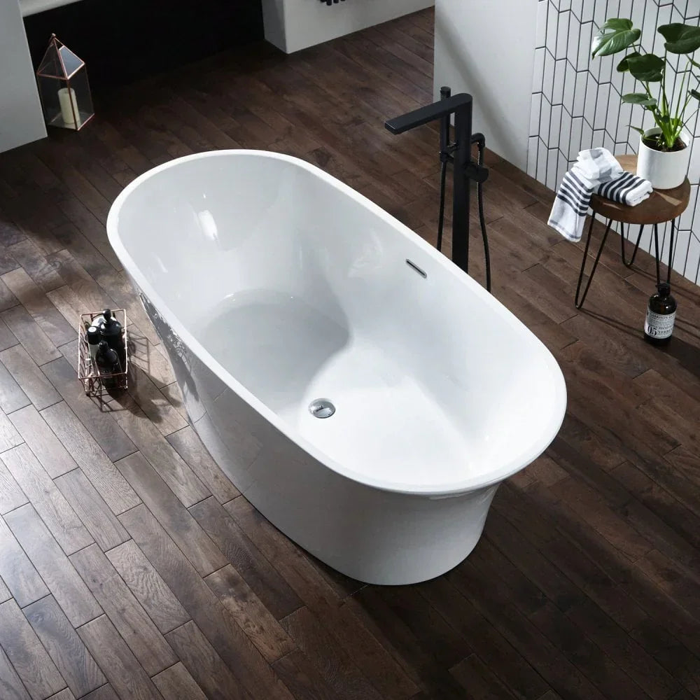 Freestanding white bathtub on dark wood floor with modern black tap and side table
