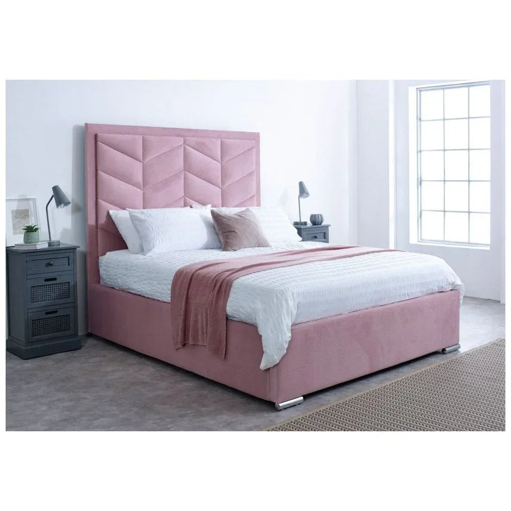Pink upholstered bed frame with chevron headboard, white bedding, and grey bedside tables