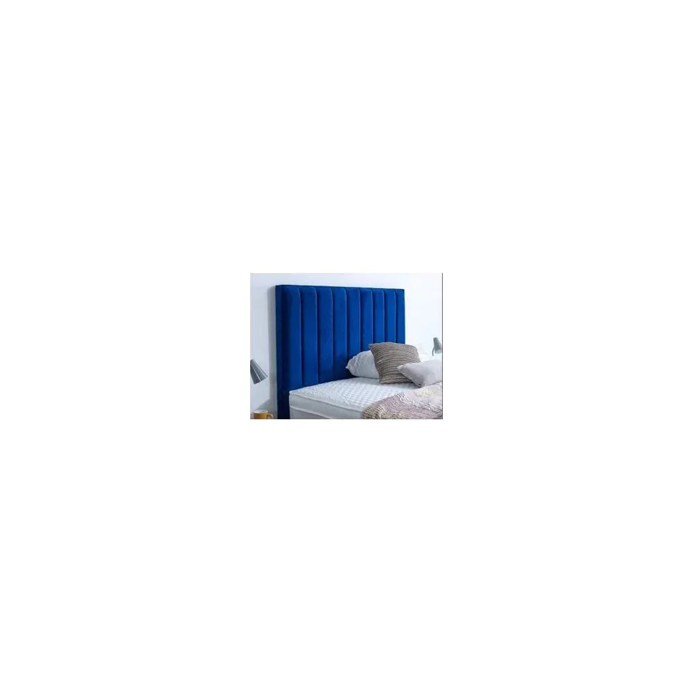Blue velvet upholstered headboard with vertical panels behind bed and pillows