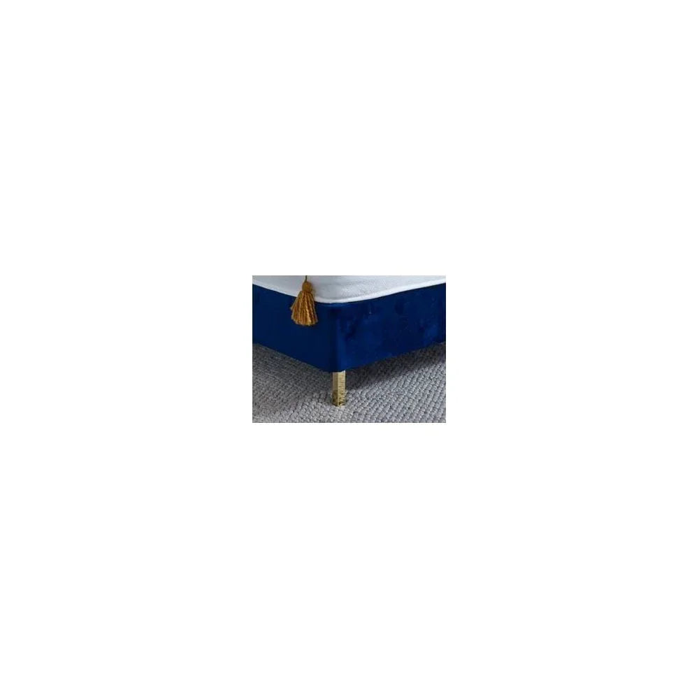 Blue velvet bed base corner with gold leg and yellow tassel on grey carpet