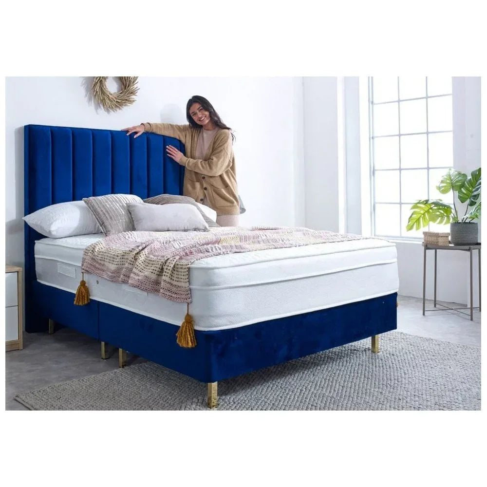 Velvet blue bed frame with tall headboard, layered bedding and gold legs in bright bedroom