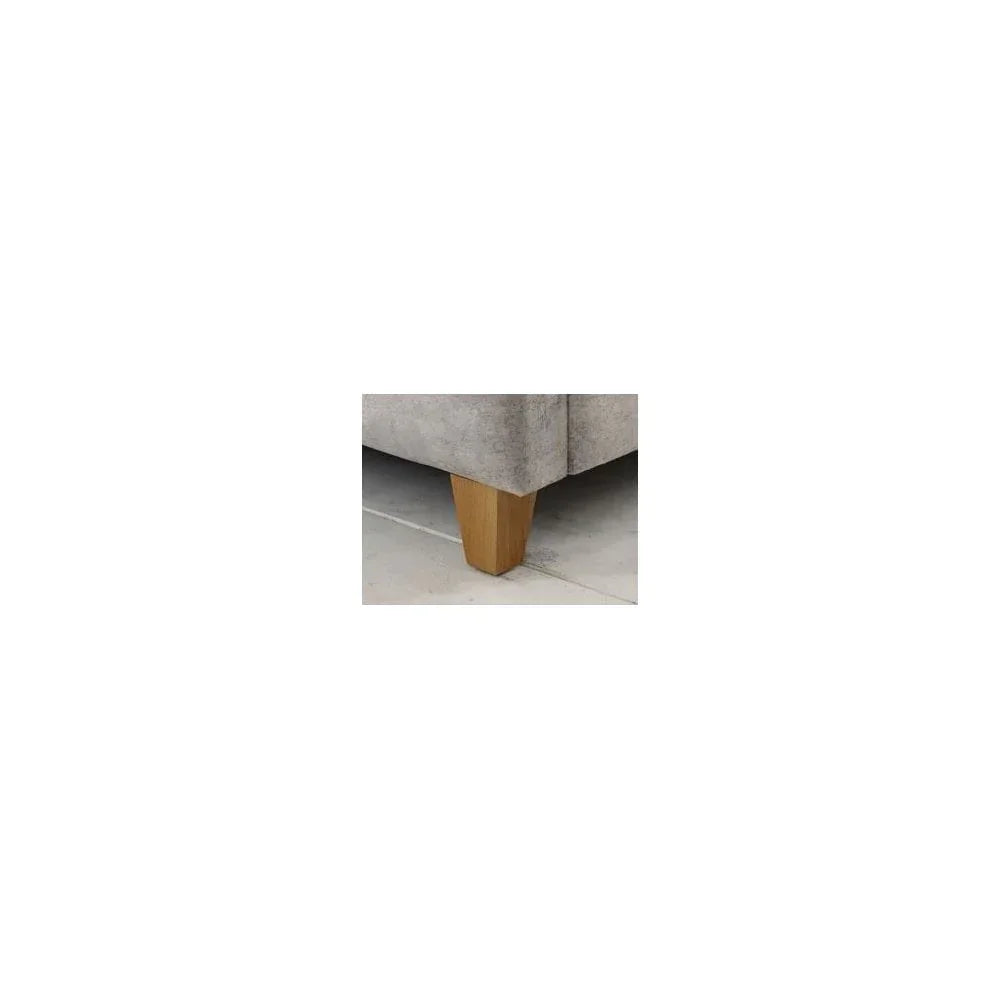 Light wood tapered sofa leg on grey upholstered base on tiled floor