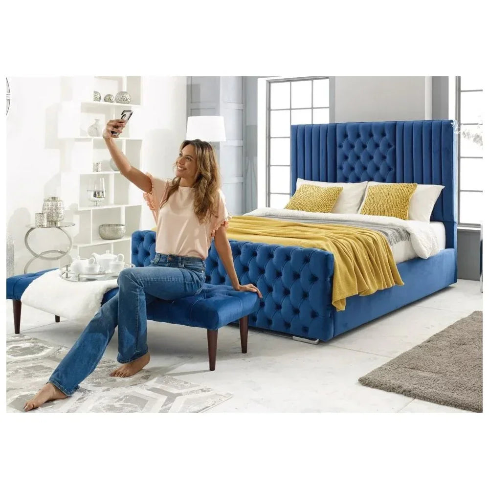 Blue velvet upholstered bed with tall headboard, matching bench, and yellow throw blanket